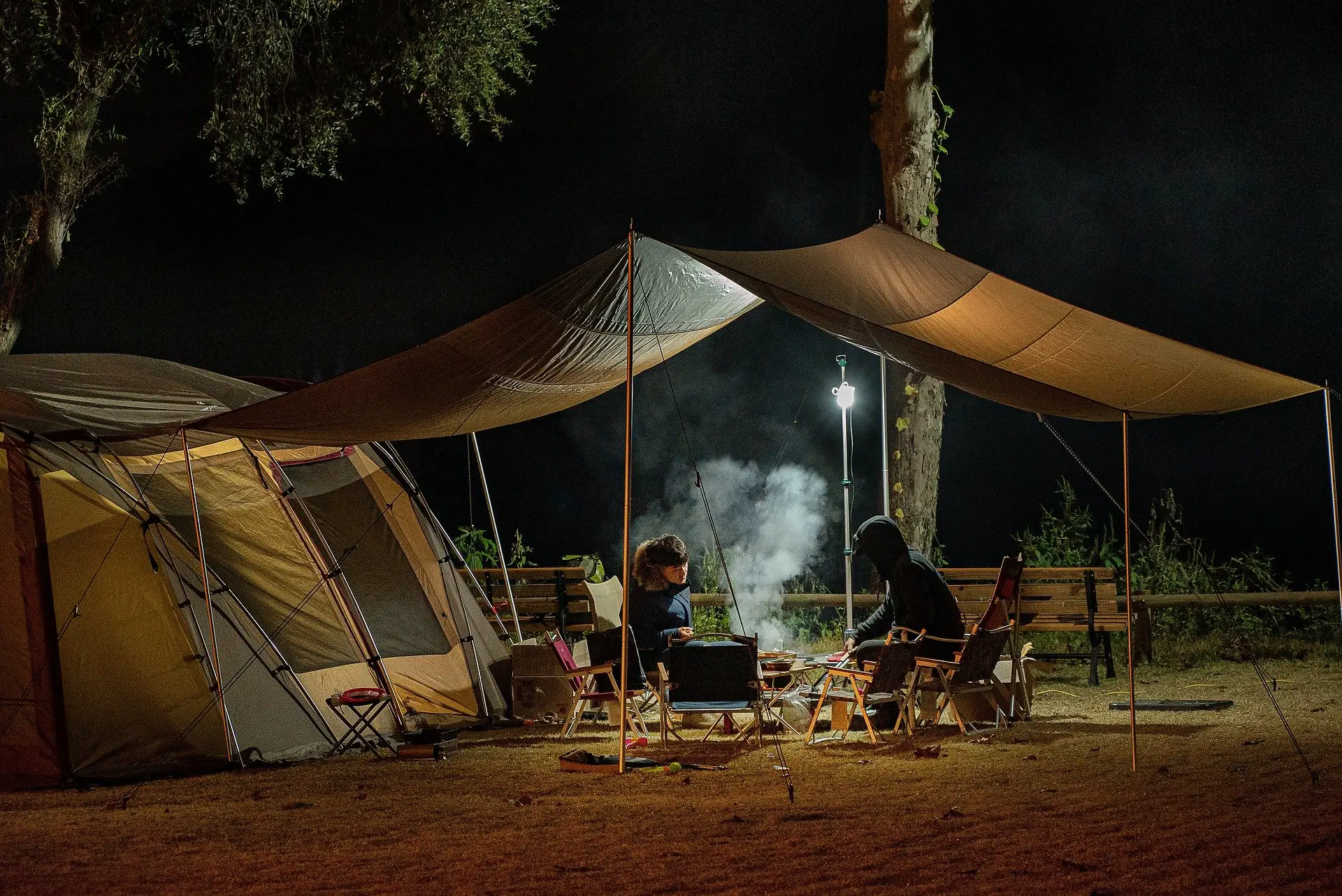 people sitting outside a tent at night