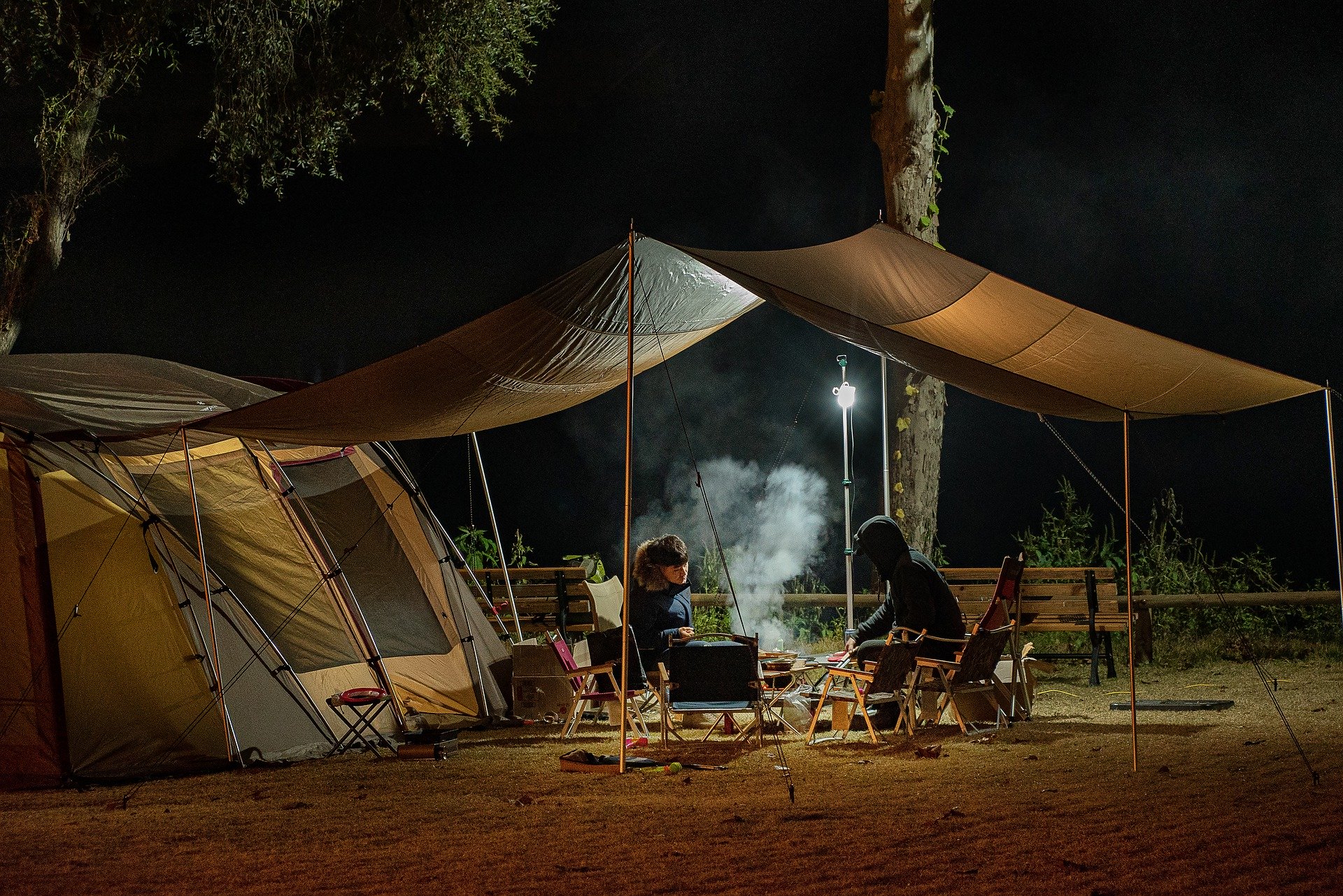 people sitting outside a tent at night