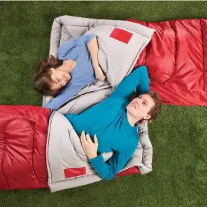 people laying in red sleeping bags on grass