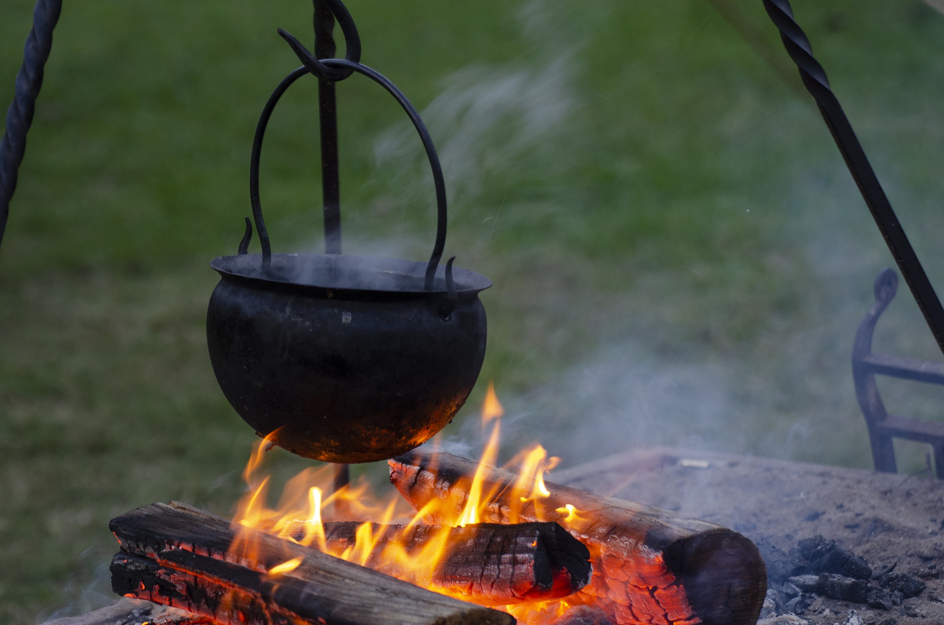 black cauldron on tripod over campfire