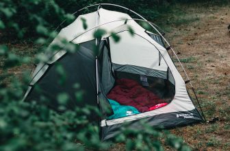 gray dome tent with green and red sleeping bags inside