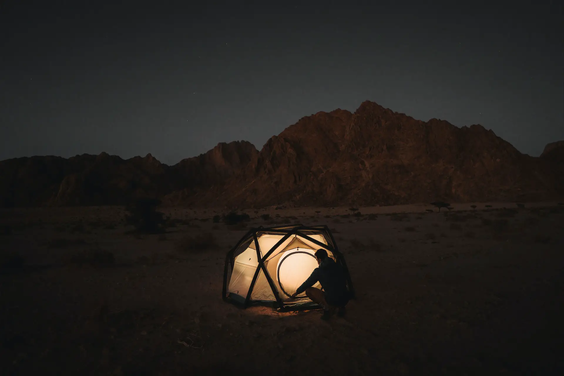 silhouette of a person alone in a tent at night
